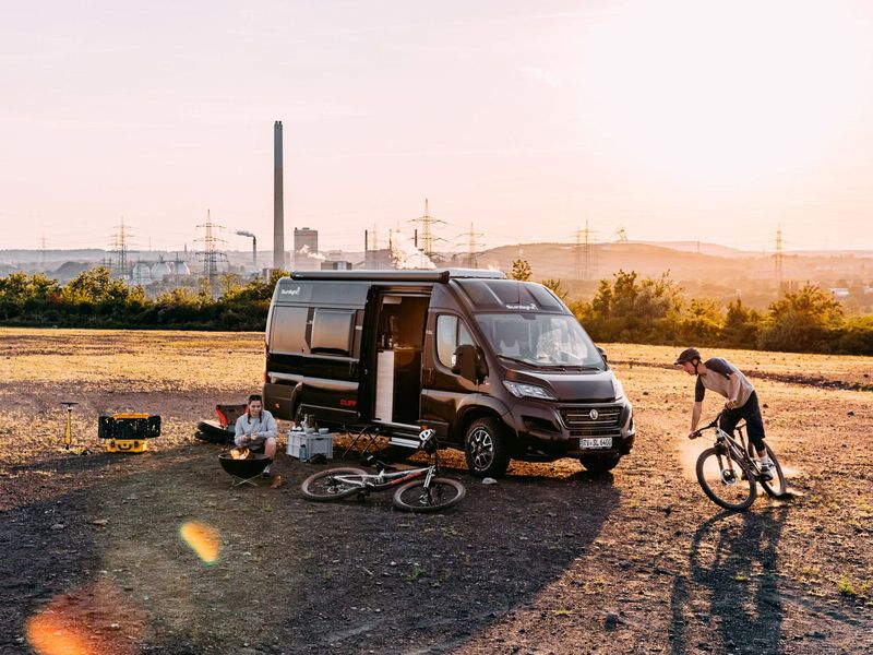 Wohnmobil mieten Sunlight Cliff Adventure abgebildet auf einer Weise beim Camping mit 2 Personen und Fahrrädern. Der Grill wird vorbereitet